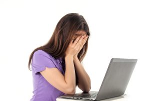 Femme qui se tient le visage devant son ordinateur car elle est fatiguée.
